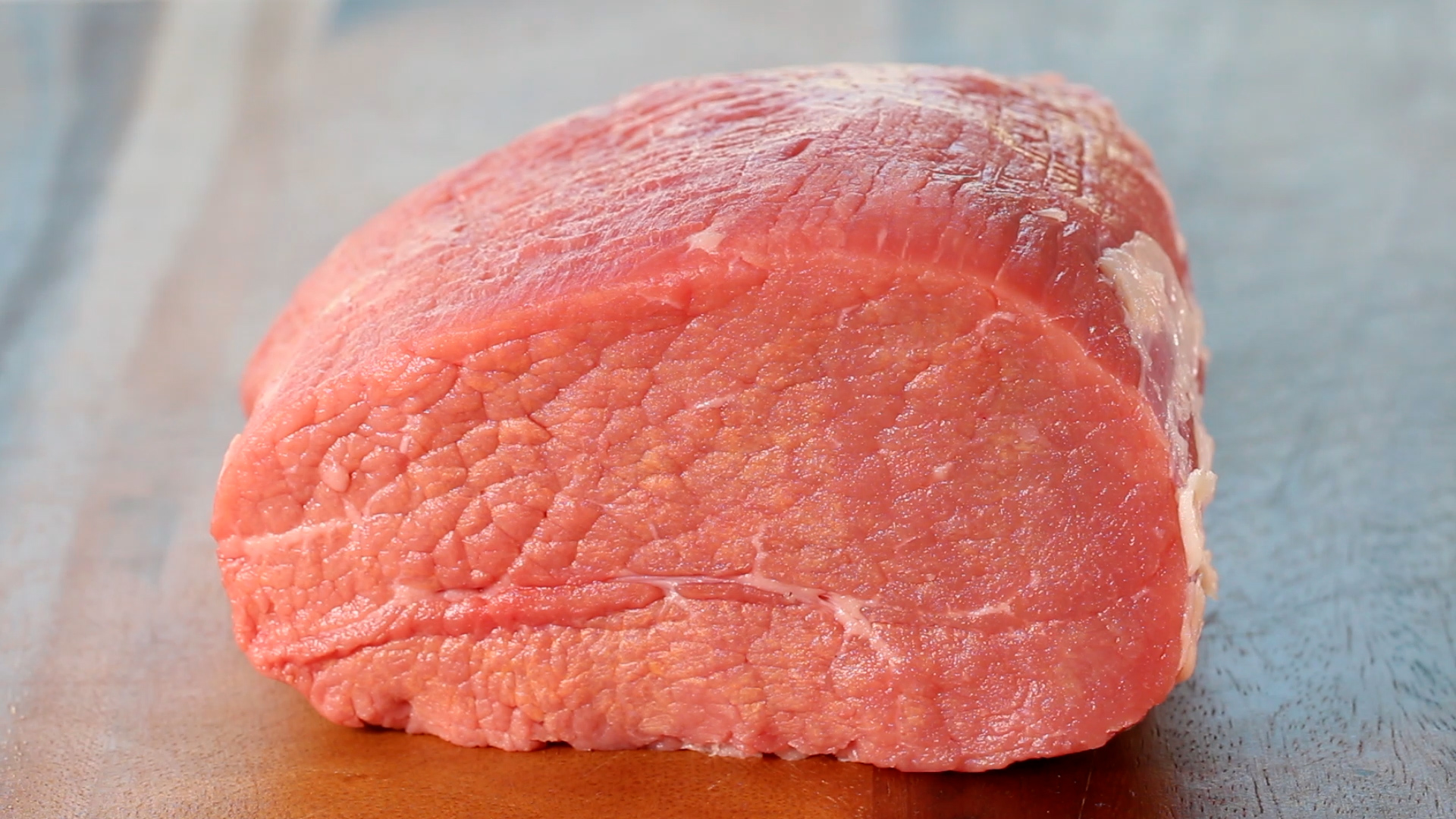 An eye of round roast on a cutting board awaiting to be sliced into steaks.