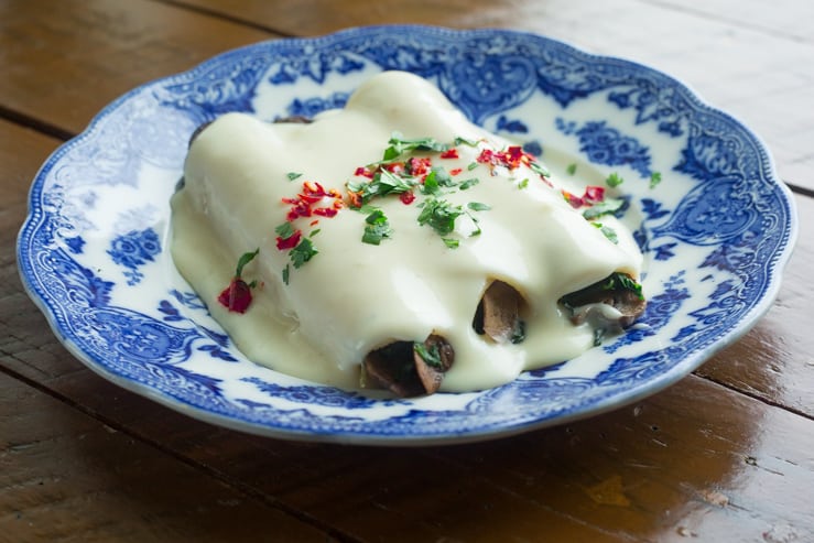 Spinach and Mushroom Enchiladas with Cream Sauce on a blue antique plate