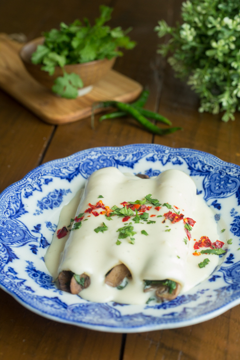 Enchiladas de Espinacas y Champiñones con salsa de crema sobre una mesa de madera