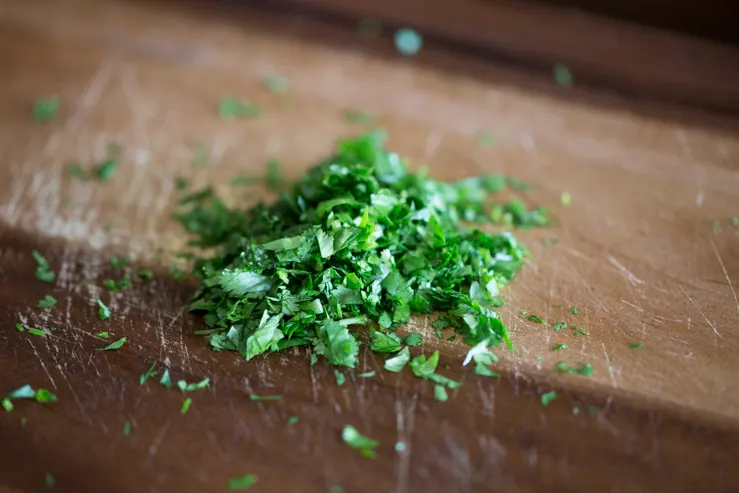 Freshly minced cilantro on a wooden cutting board