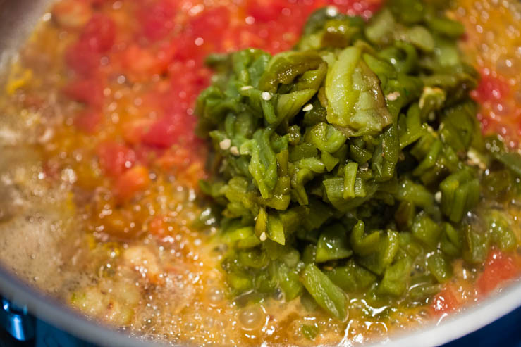 Green chiles and tomatoes sizzling in a buttered pot for the Torchy's Queso Recipe