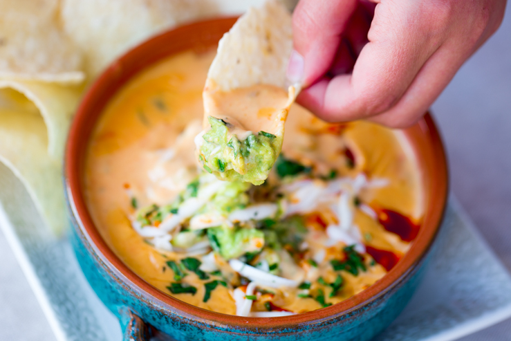 A chip scooping into the bowl of torchy's queso 