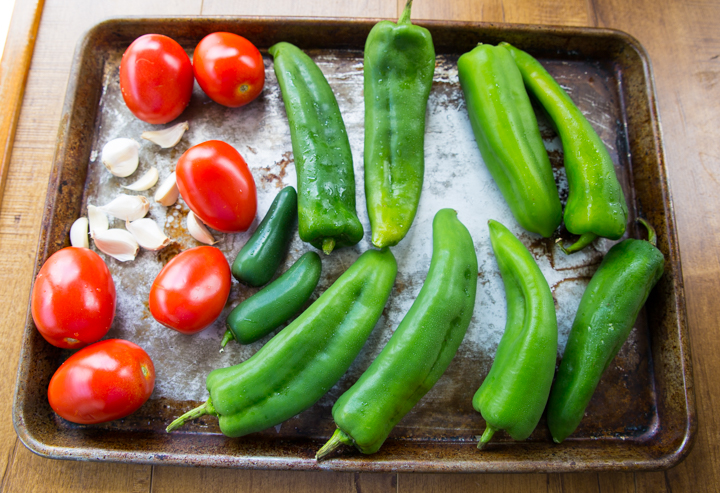 Chiles, tomatoes, and garlic, on a sheet pan about to be roasted for queso