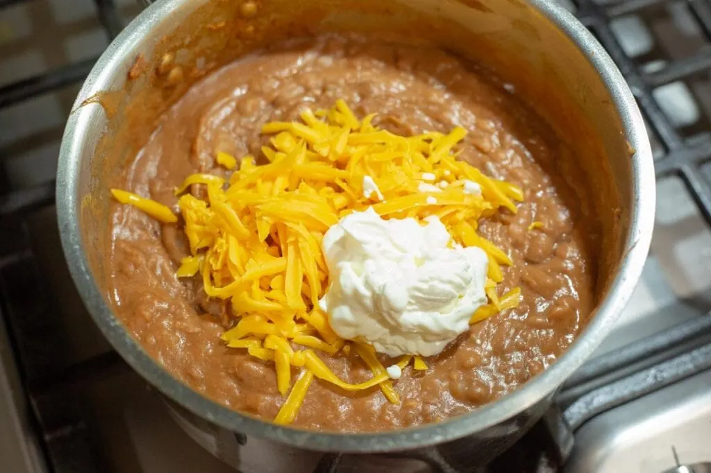 Adding cheddar cheese and sour cream to the pinto beans
