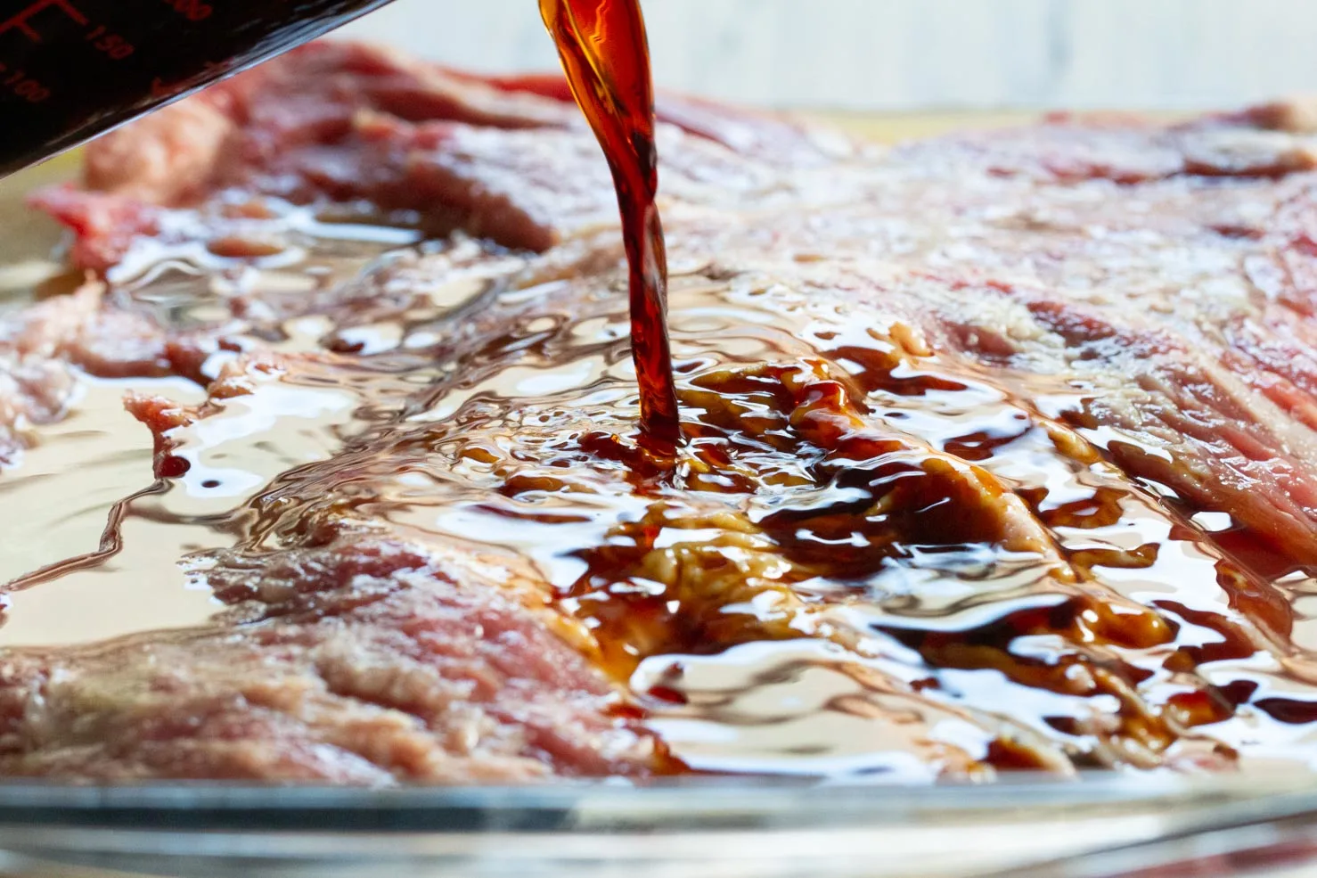 Soy Sauce being poured over the skirt steak for the marinade