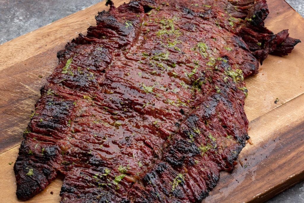 A slab of grilled Texas style skirt steak fajitas resting on a cutting board