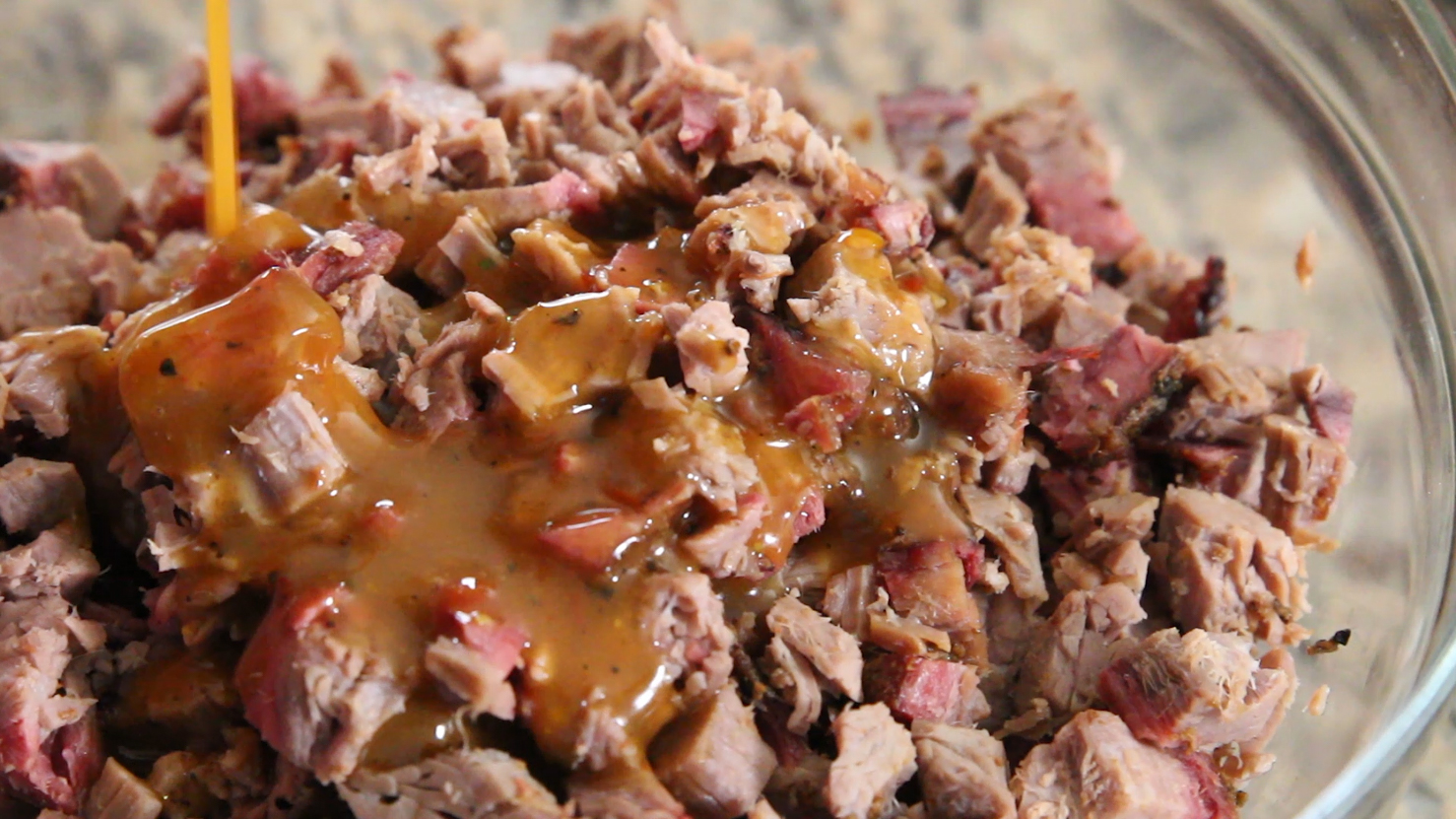 Chopped brisket being sauced with our dr pepper barbecue sauce