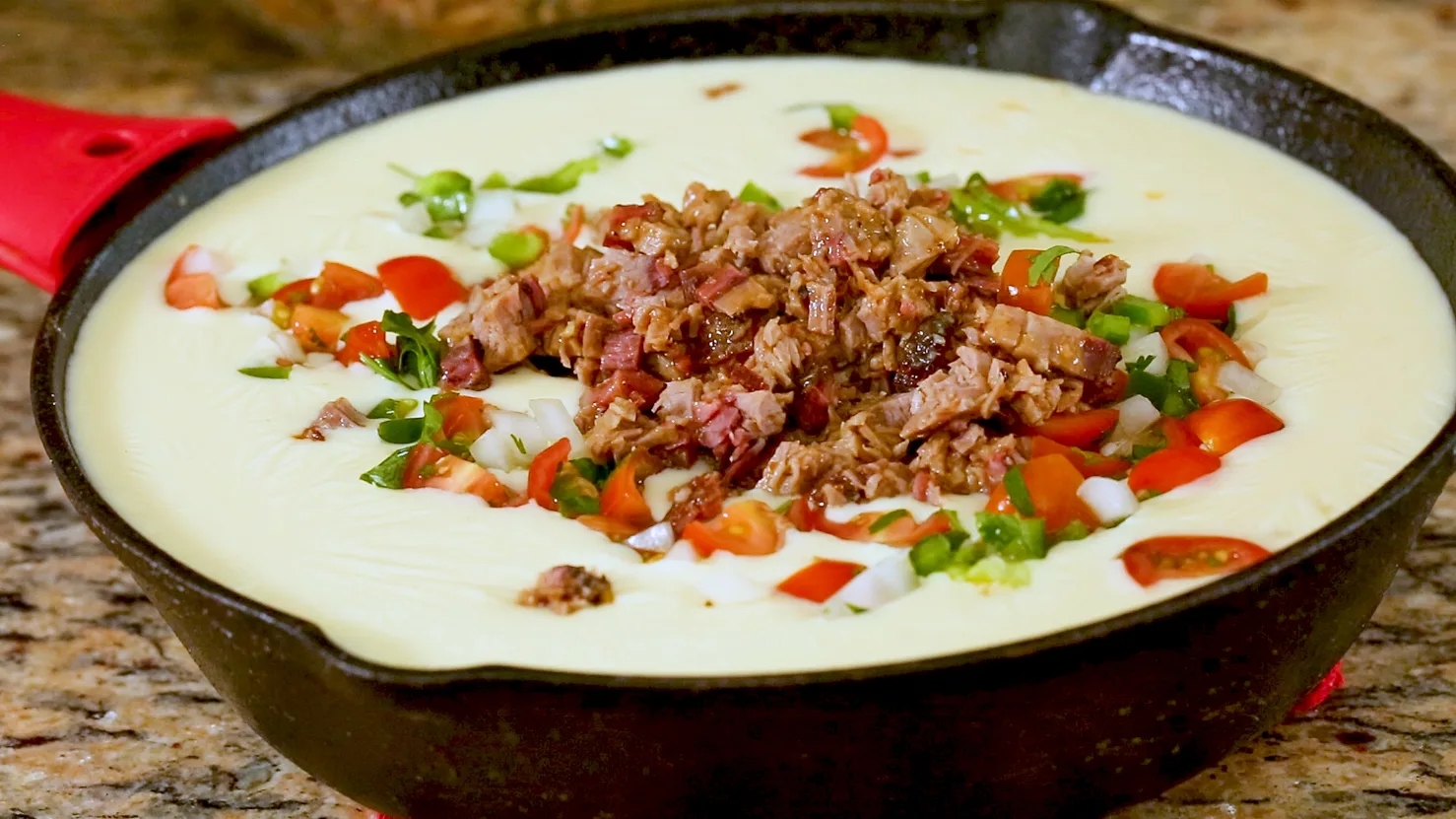 A beautiful photo of Texas brisket queso topped with pico de gallo and fresh brisket