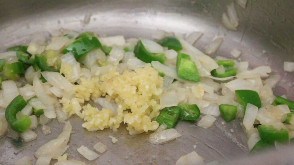 Adding garlic to the pot of queso