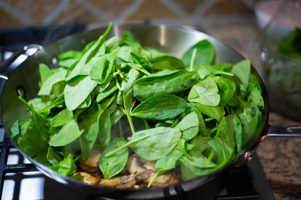 Adding spinach to the mushrooms 