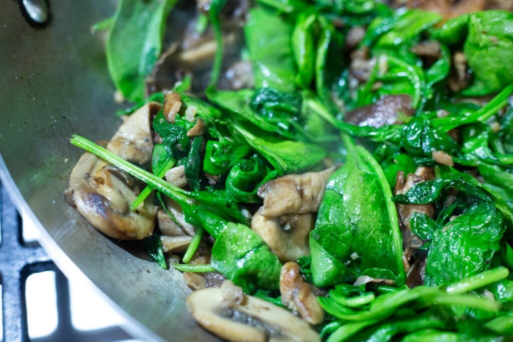  Épinards cuits et flétris avec la garniture d'enchilada aux champignons 