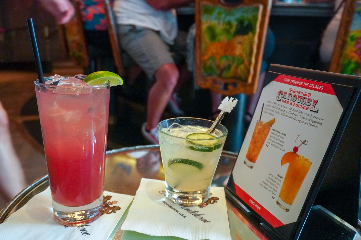 A table at the Carousel bar in New Orleans with a pink cocktail and a cucumber cocktail waiting for you to take a drink.