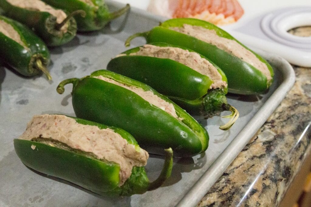 Stuffed Jalapenos preparing to be wrapped with bacon 