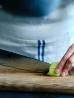 A woman in an apron chopping vegetables