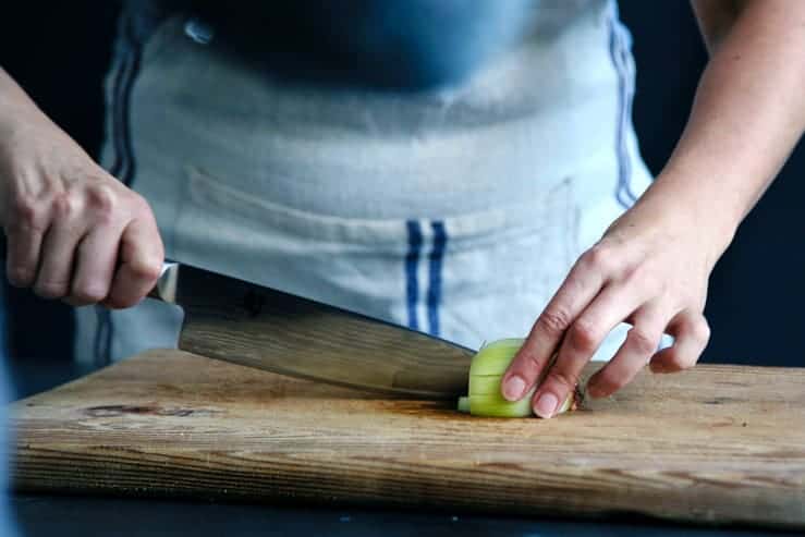 A chef chopping an onion in a white and blue apron