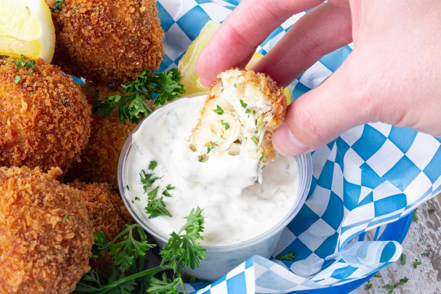 A crab ball being dipped in sauce.