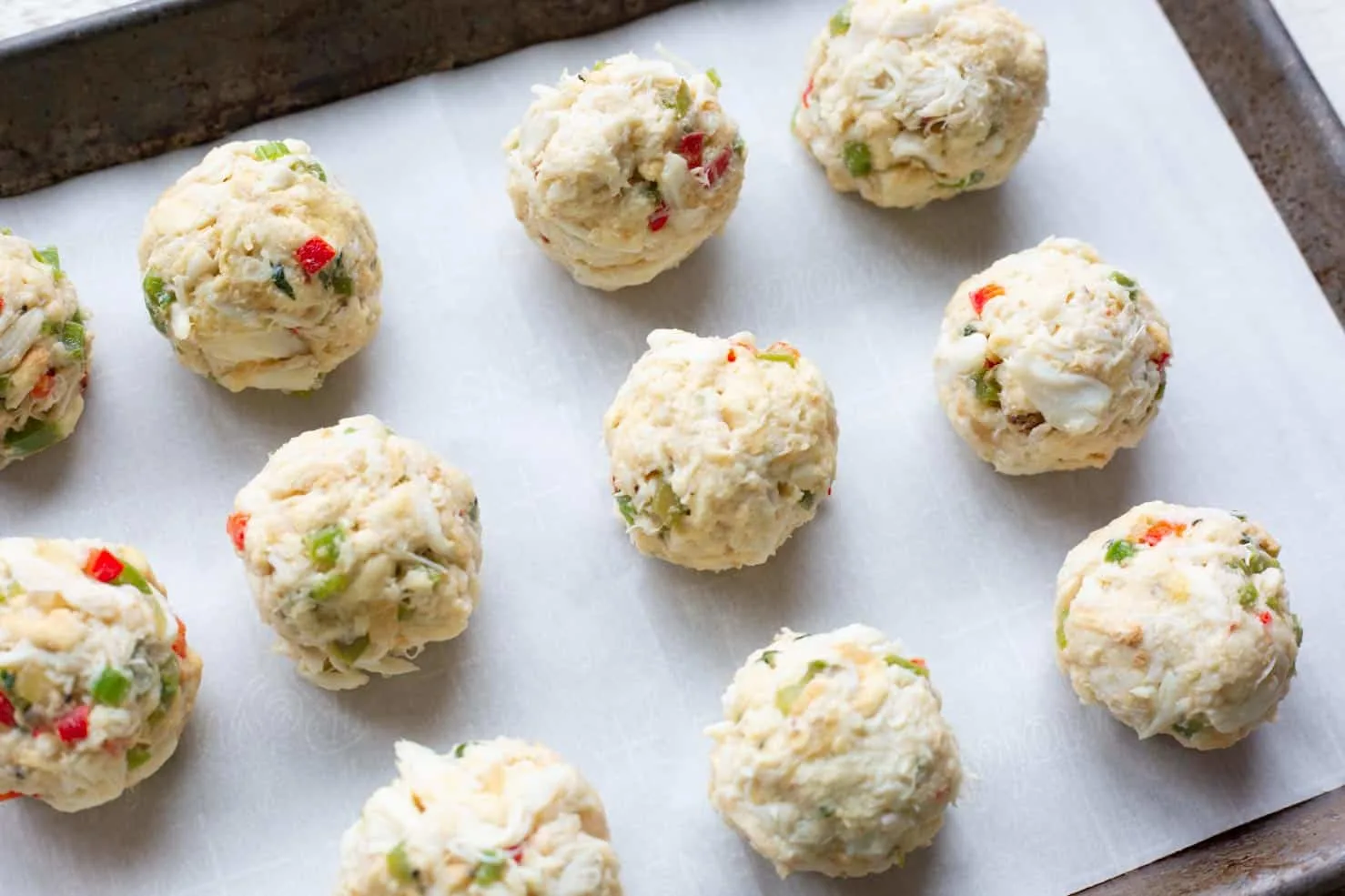Rolled crab balls on a baking sheet before breading.