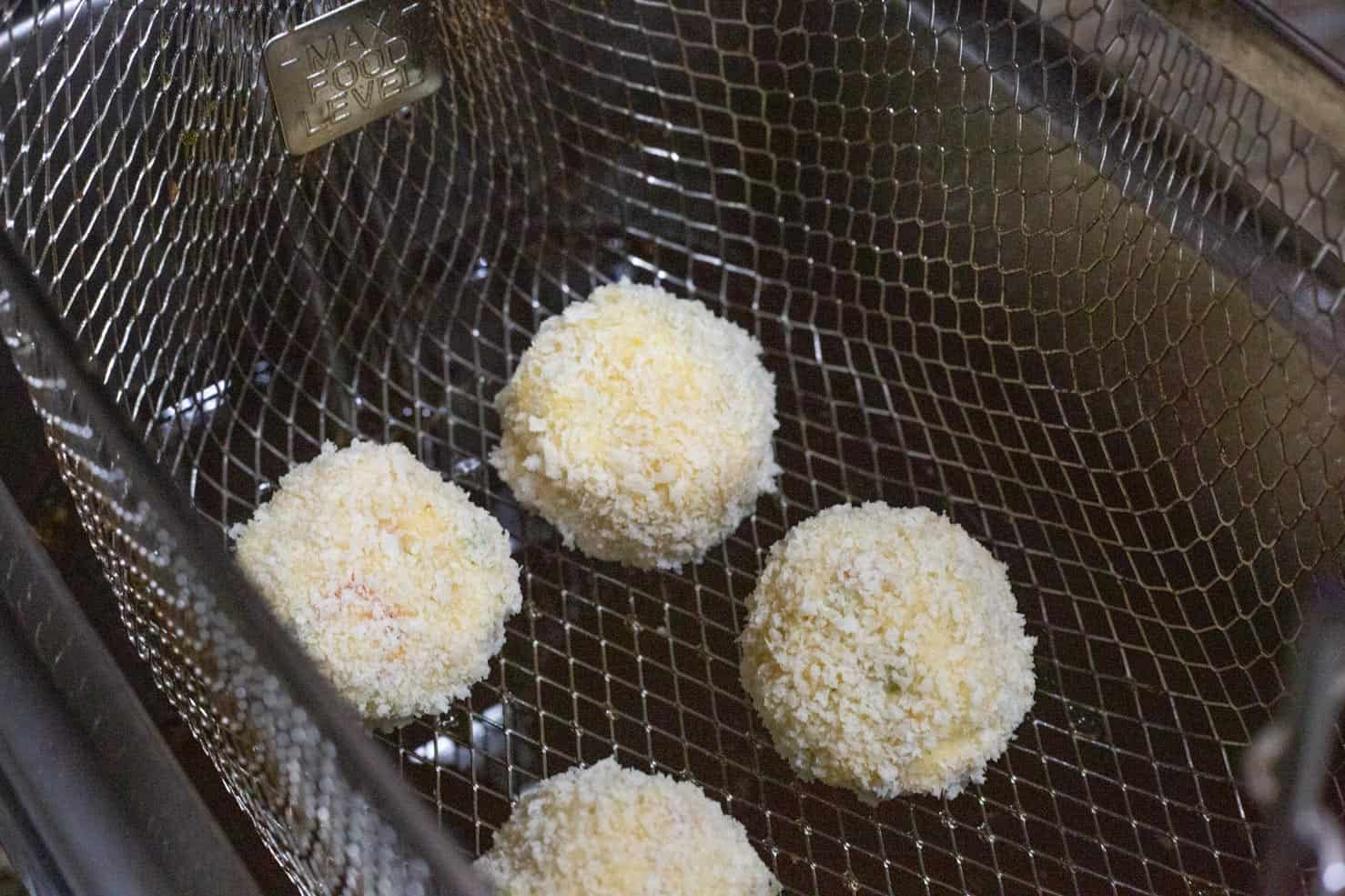 Uncooked crab balls in the basket of the fryer.