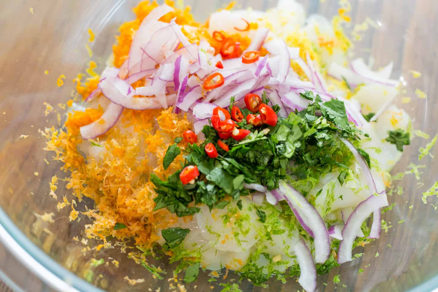 All of the colorful ingredients for ceviche in a glass bowl