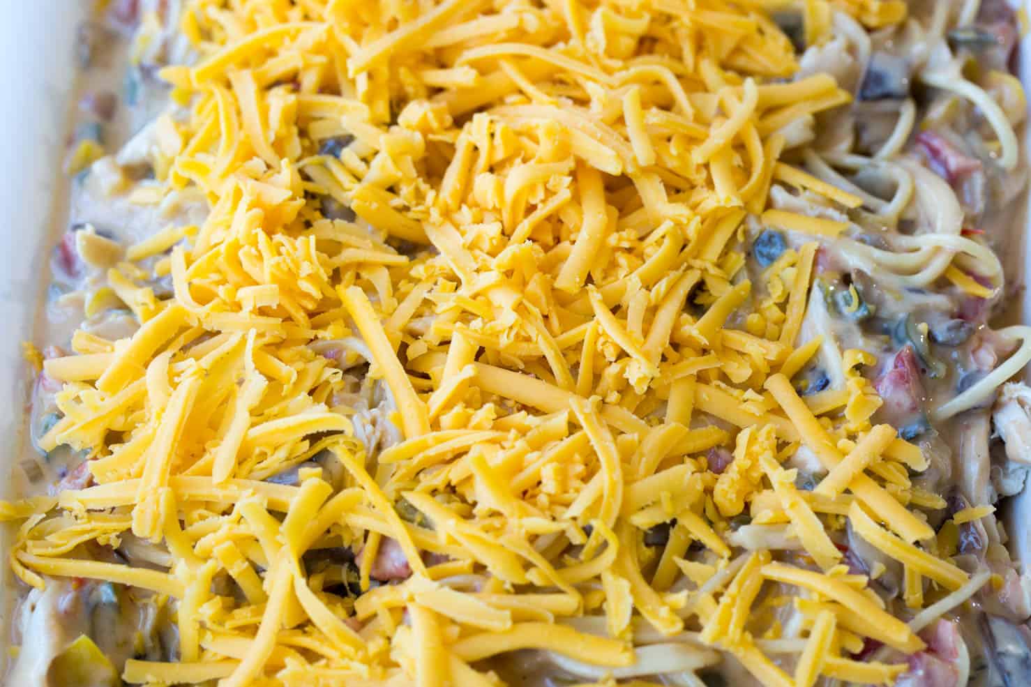 A close up of the uncooked pasta topped with shredded cheese and ready for baking.