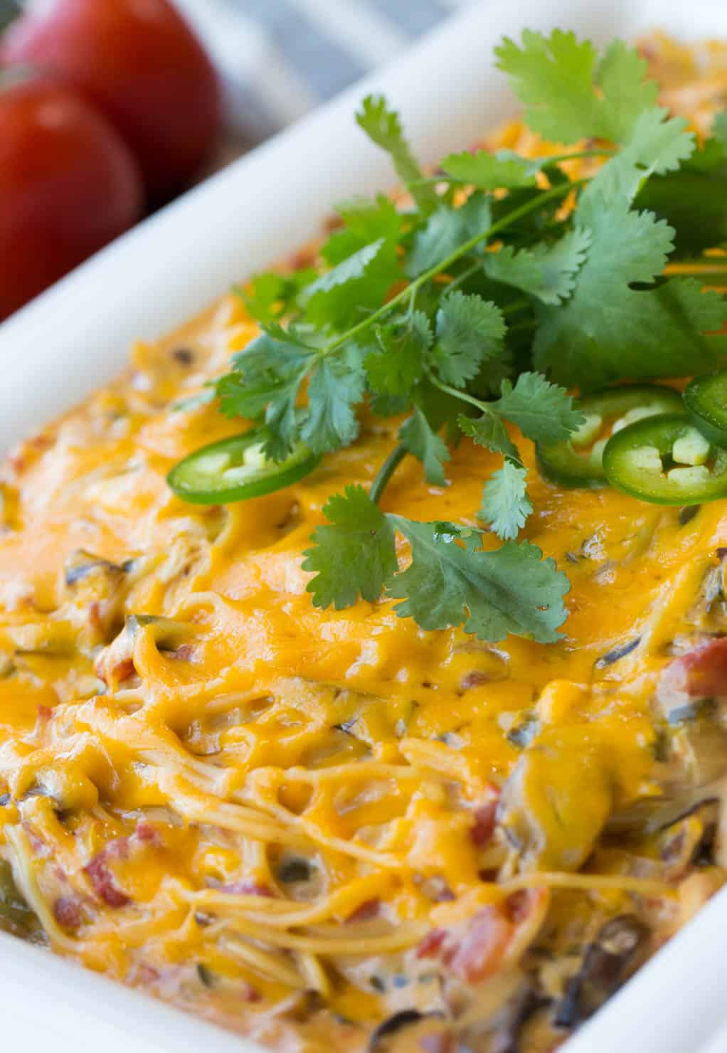 A completed cheesy chicken spaghetti casserole, baked and covered with cheese, topped with cilantro. 