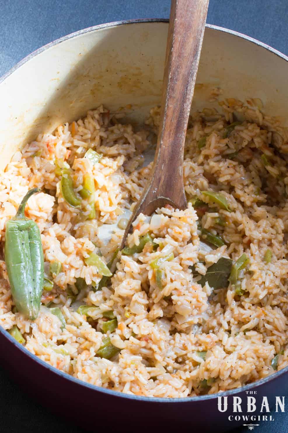 A full pan full of mexican rice with a wooden spoon. 