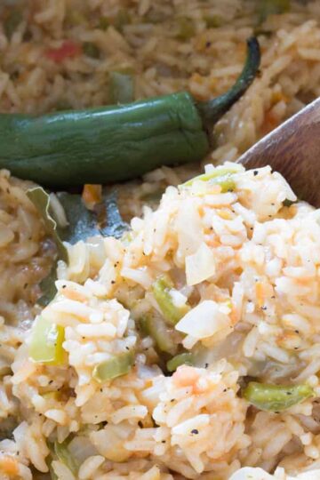 A wooden spoonful full of fluffy mexican rice with peppers.