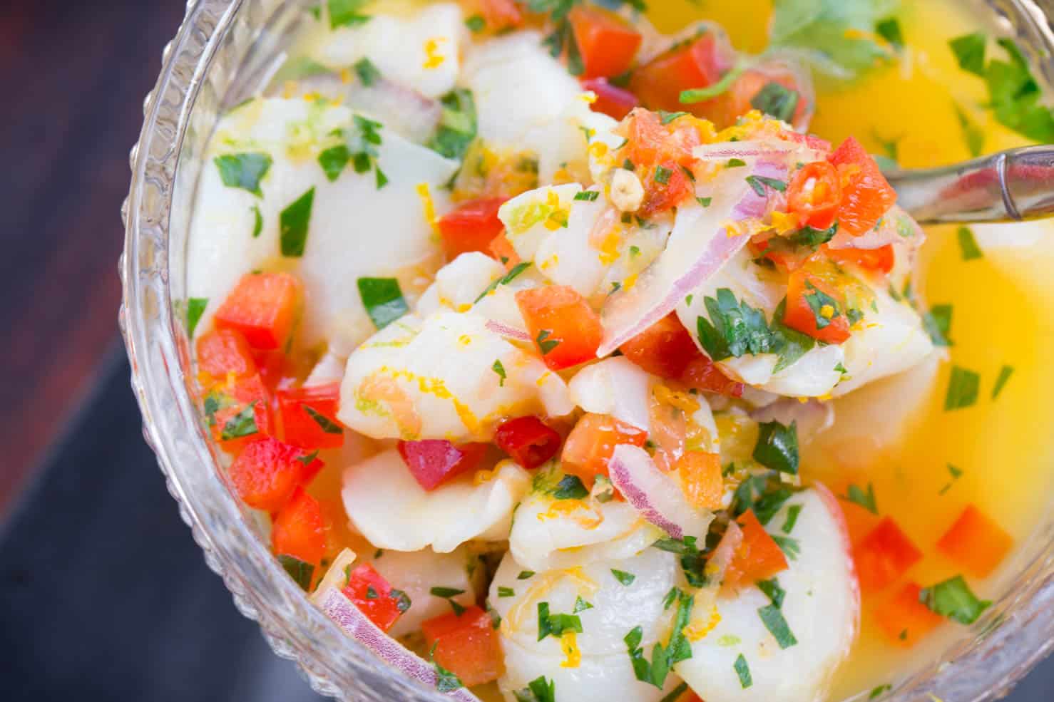 A close up of scallop ceviche with red bell peppers and cilantro 
