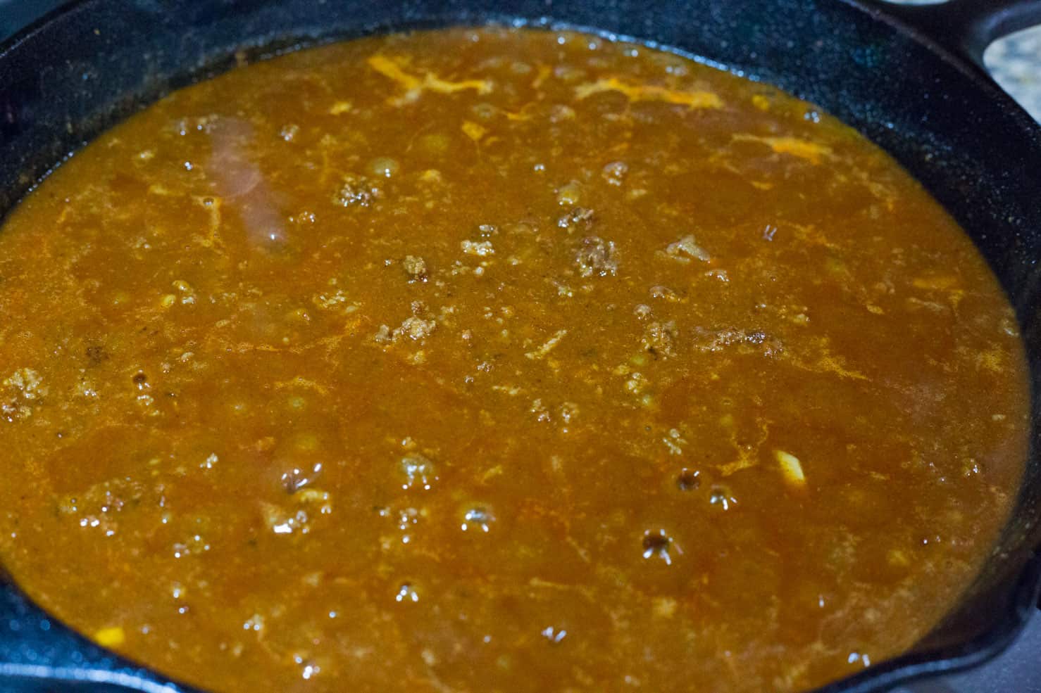 A skillet filled with cooked chili gravy bubbling.