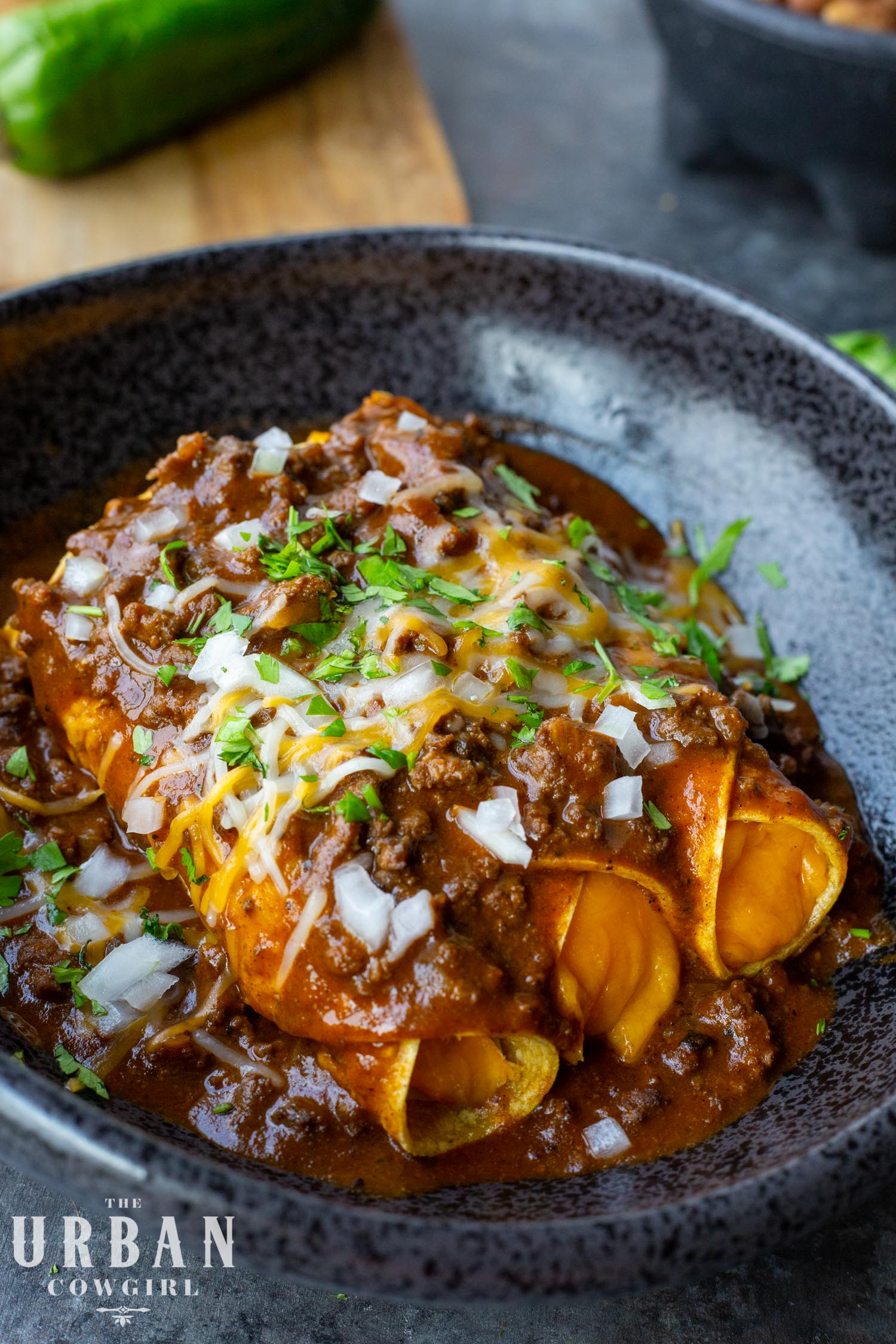 tex mex cheese enchiladas with chili gravy on a black plate