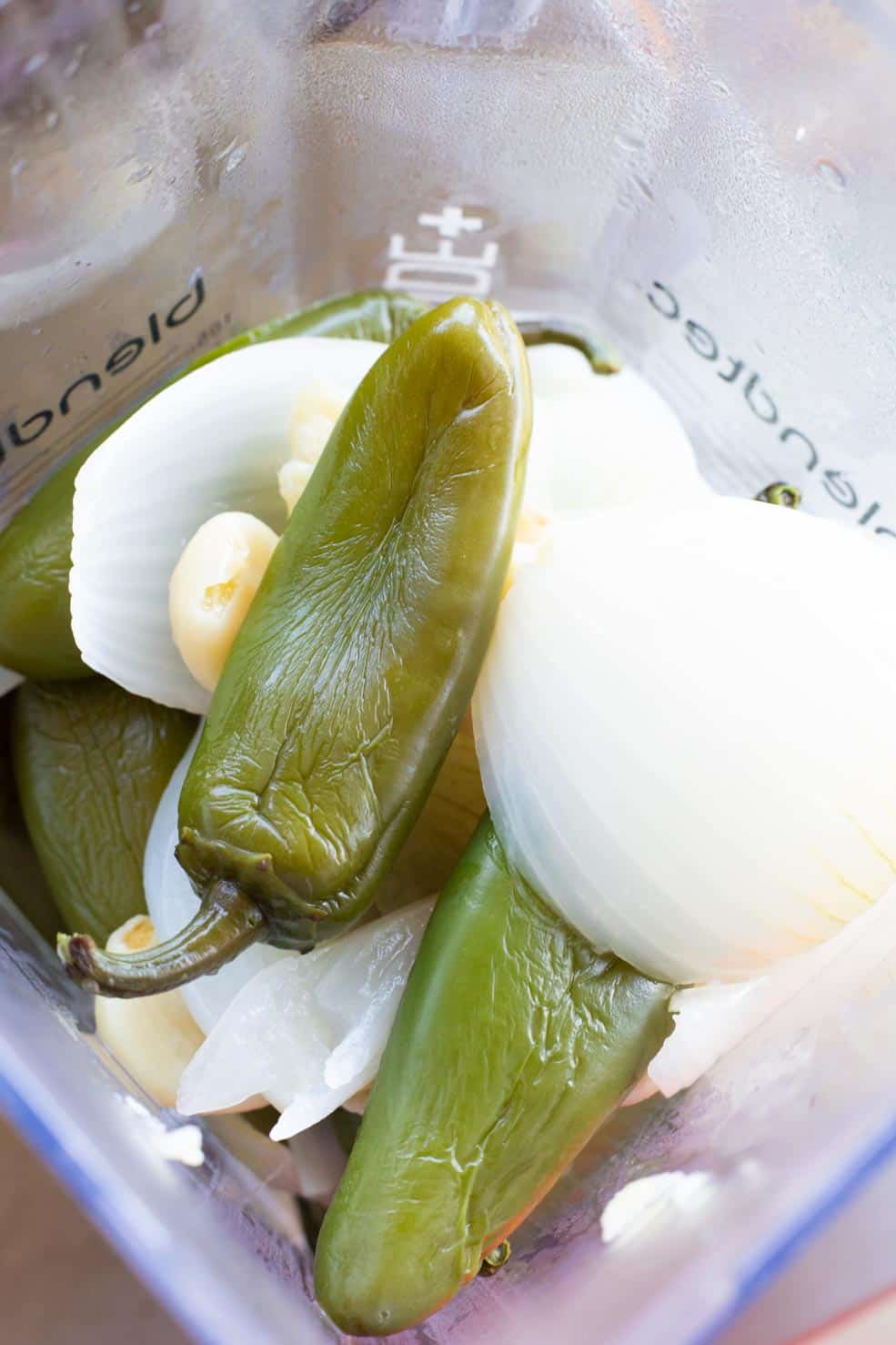 A blender full of the cooked jalapenos and vegetables waiting to be blended.