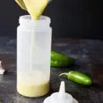 creamy jalapeno sauce being poured from the blender into a squeeze bottle