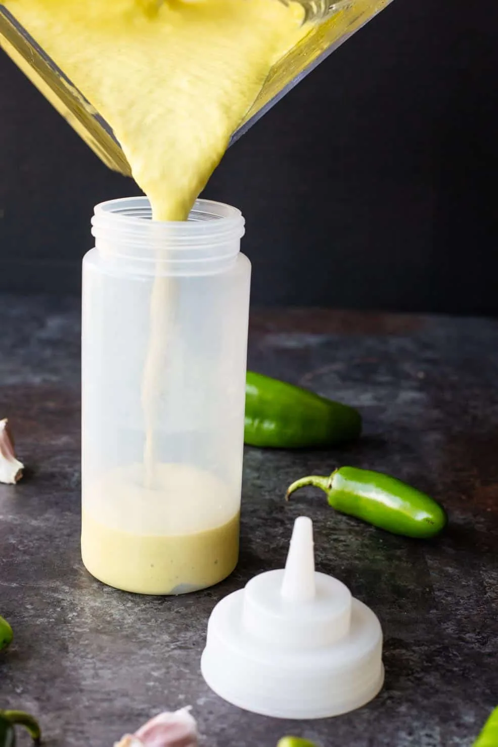 Fiery jalapeno sauce being poured into a wide mouthed bottle.