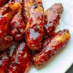 A plate of juicy, red, smoked chicken wings in strawberry barbecue sauce