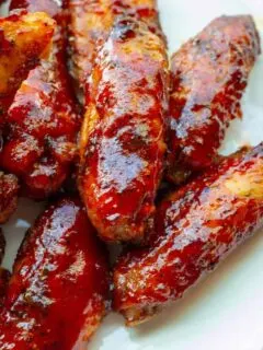 A plate of juicy, red, smoked chicken wings in strawberry barbecue sauce