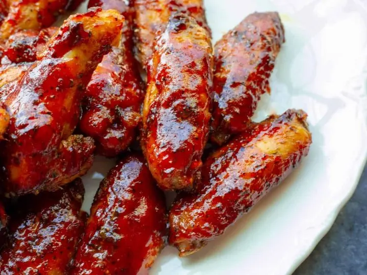 A plate of juicy, red, smoked chicken wings in strawberry barbecue sauce