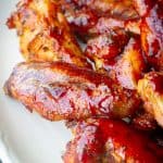 A plate of red and juicy strawberry barbecue wings