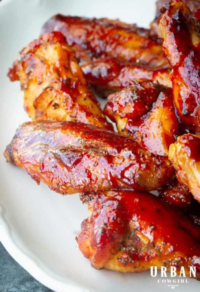 A white plate full of juicy smoked chicken wings, fresh from the barbecue smoker.