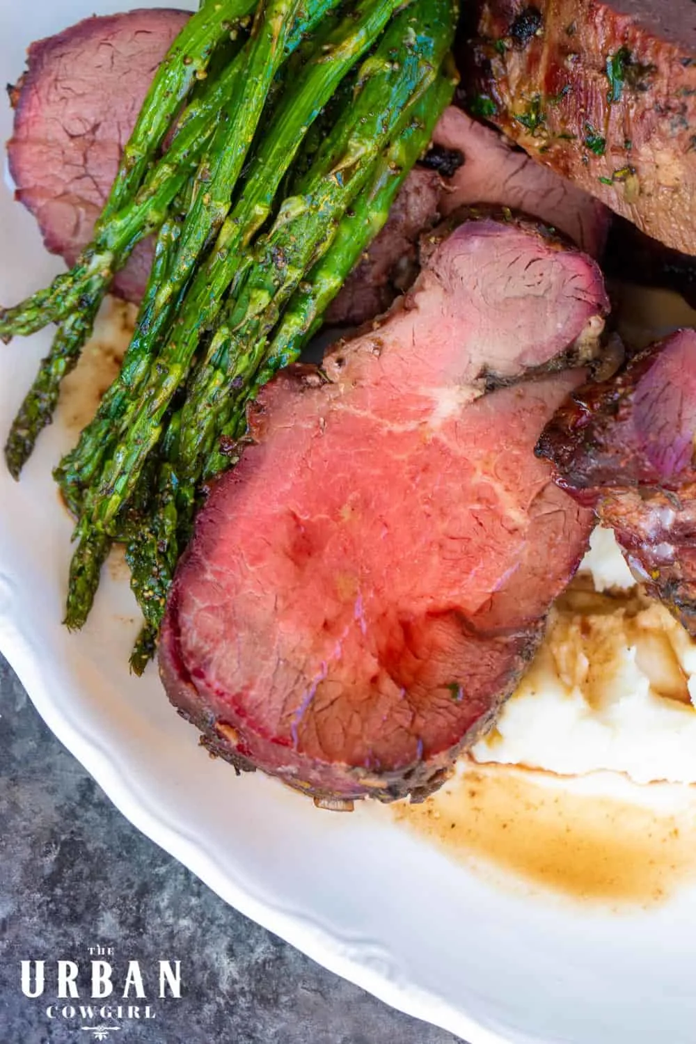 Smoked Beef Tenderloin on a platter with asparagus.