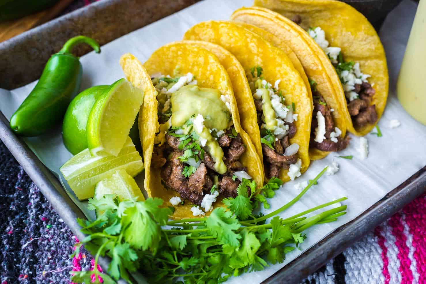 A pan of steak street tacos covered in a creamy jalapeno sauce