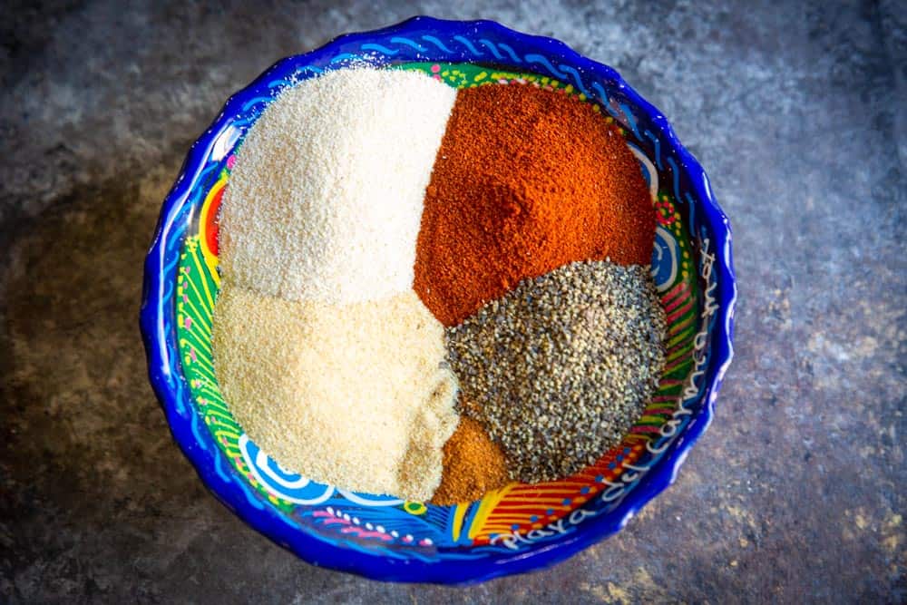 A colorful bowl filled with 5 different bright spices.