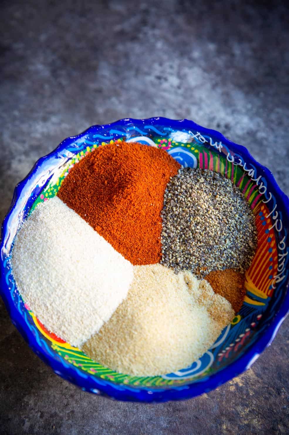 A close up of chili powder and various other spices which commonly go in carne asada seasoning. 