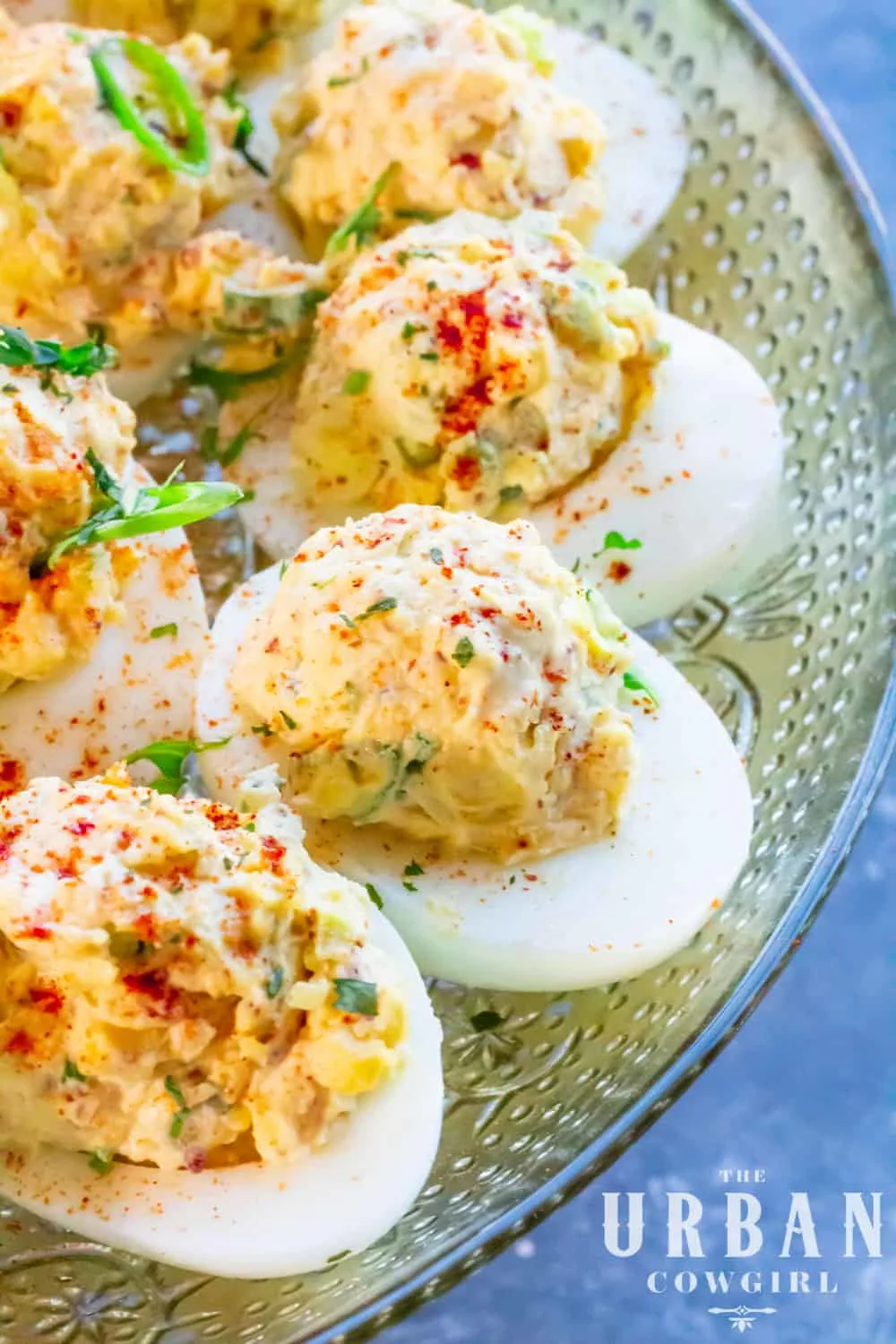 A long, large platter of cajun deviled eggs sprinkled with herbs.