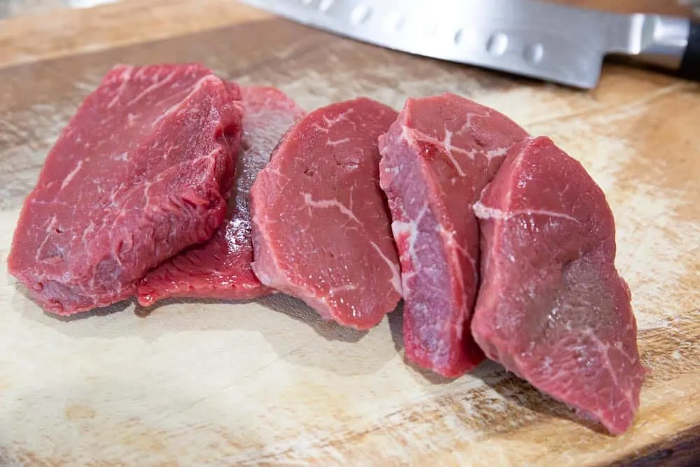5 thin sirloin steaks on a cutting board