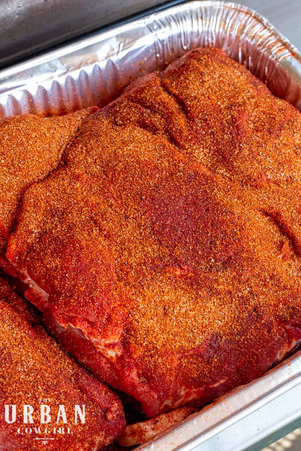 a pork butt covered in pork rub in a pan ready for the smoker. 