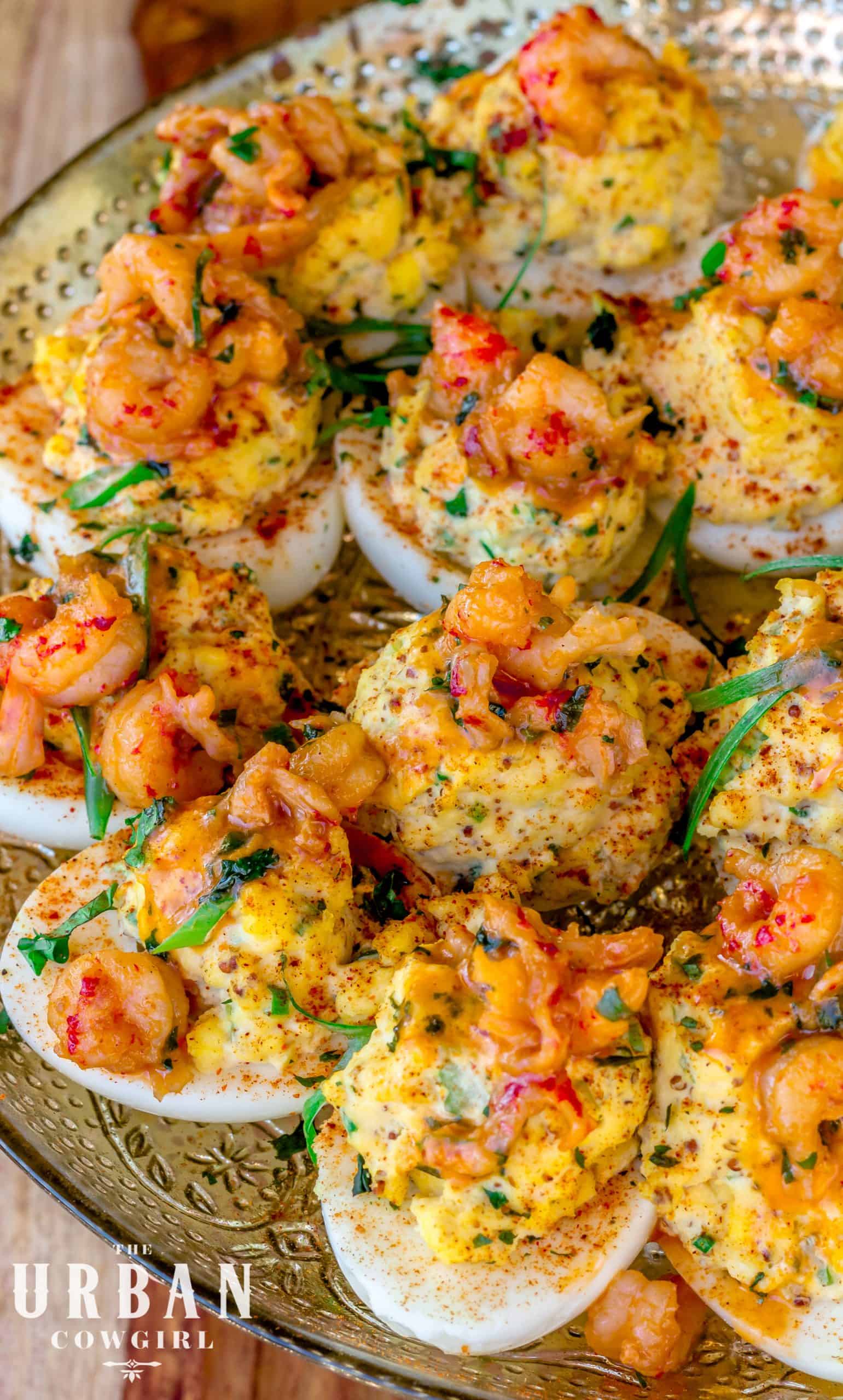 A loaded up platter of many deviled eggs with crawfish topping.