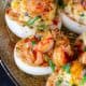 A close up of loaded crawfish deviled eggs on a silver platter.