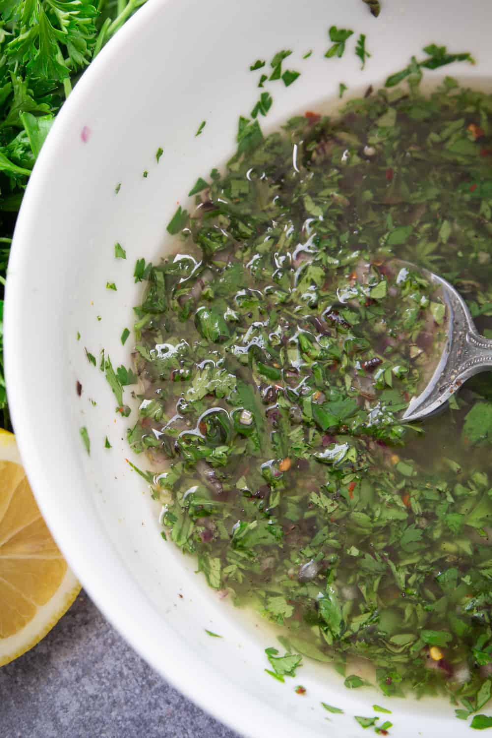 A close up of chimichurri sauce with fresh herbs, garlic, lemon juice, red onion, and Mazola Corn Oil