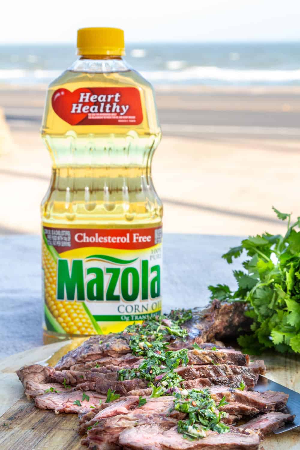 A wedge salad topped with chimichurri skirt steak in front of the ocean