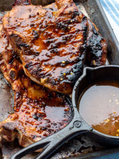 grilled pork chops on a platter with a sauce pot of glaze.